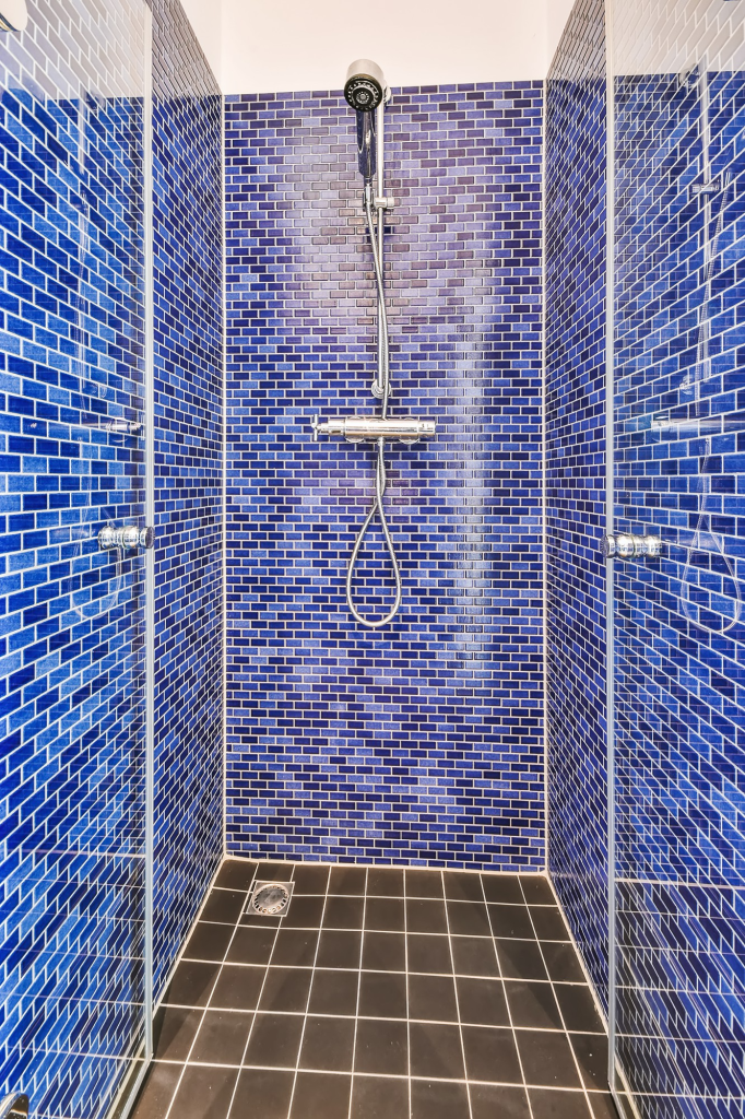 Keramik dinding kamar mandi motif mozaik pada area shower.