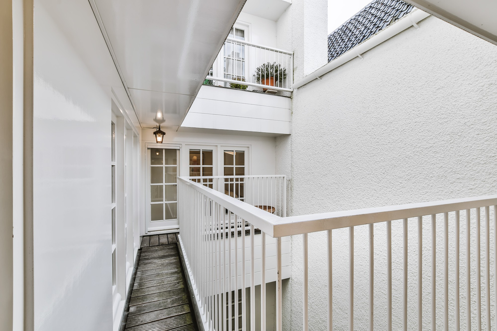 Pagar balkon besi putih bergaya Skandinavia pada rumah minimalis dengan fasad berwarna terang.