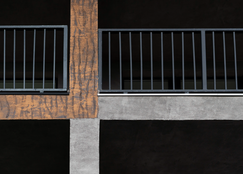 Desain pagar balkon minimalis dengan kombinasi dinding beton dan railing besi hitam pada rumah dua lantai.