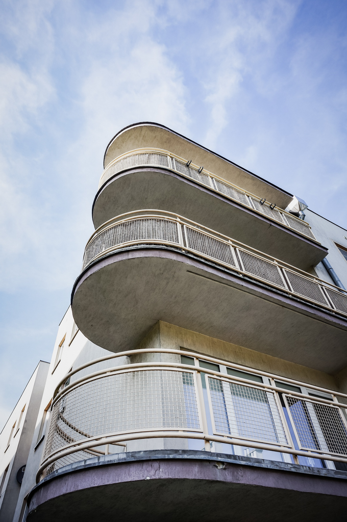 Pagar balkon logam dengan desain lengkung modern pada rumah minimalis dua lantai.