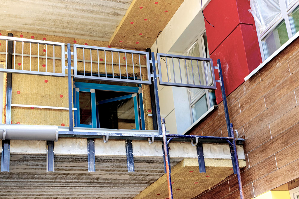 Proses pemasangan pagar balkon logam pada struktur beton rumah dua lantai dengan sistem pengikat yang sesuai.
