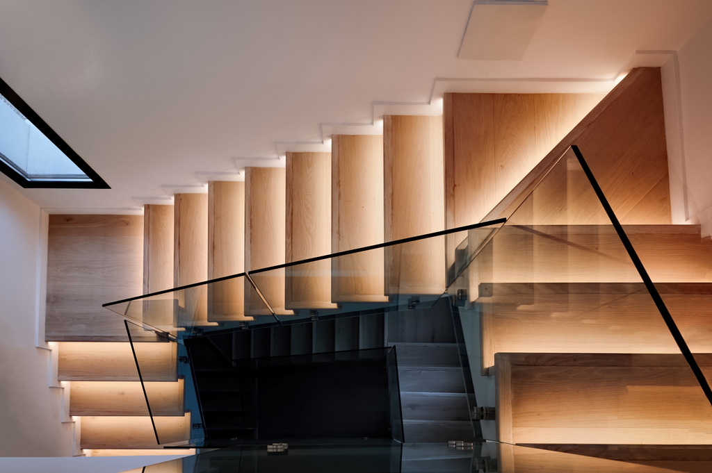 Desain tangga rumah bentuk L dengan bordes dan railing modern pada interior rumah dua lantai