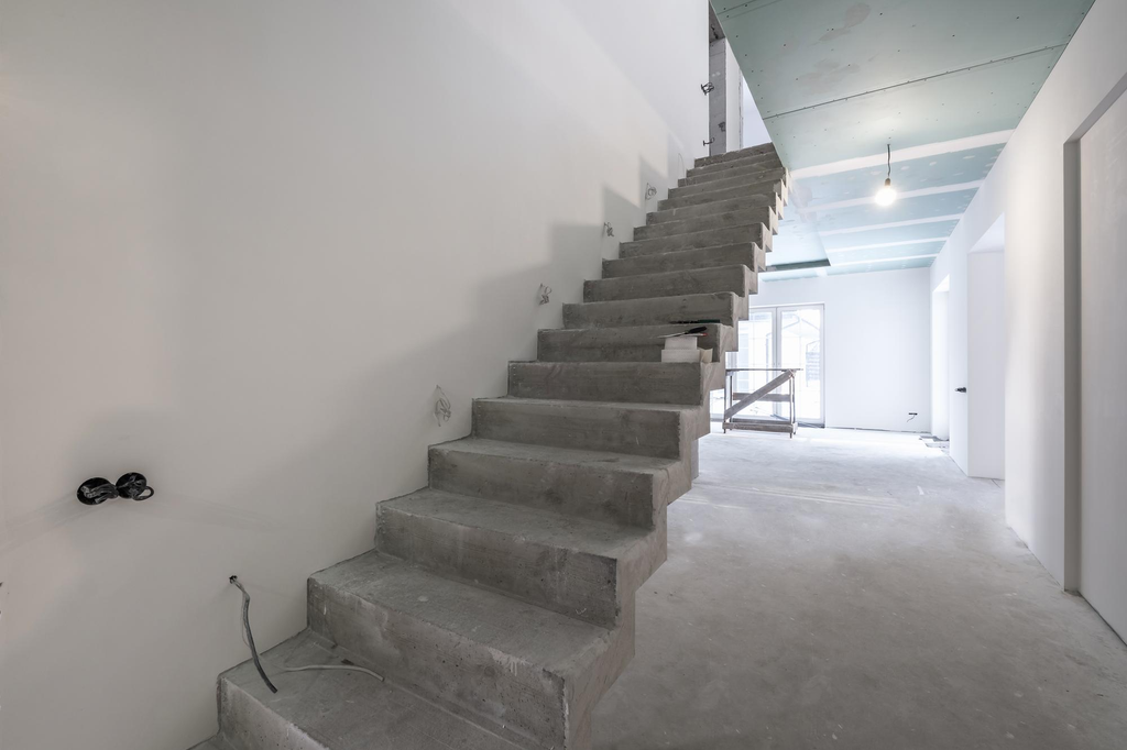 Struktur tangga beton bertulang pada rumah dua lantai sebelum pemasangan material finishing.