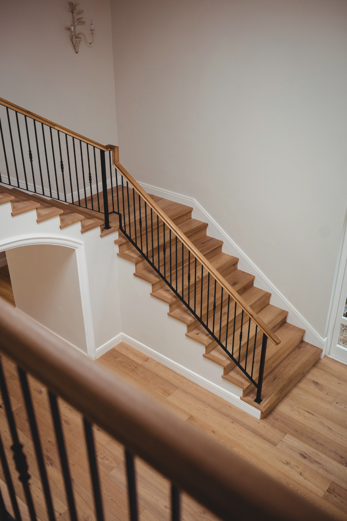 Tangga rumah berbahan kayu natural dengan desain sederhana dan railing minimalis pada interior modern.