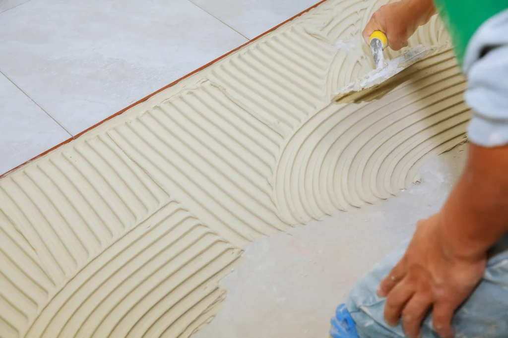 Pekerja konstruksi Asia memasang keramik lantai menggunakan perekat keramik di proyek bangunan.